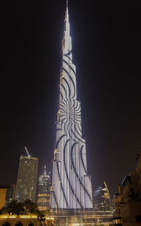 Low angle view of illuminated buildings against sky at night