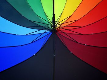 Low angle view of multi colored umbrella against blue sky