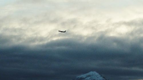 Low angle view of airplane flying against cloudy sky