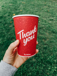 Close-up of hand holding red text on grass