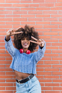 African american woman with afro hair looking at camera smiling while shows peace gesture