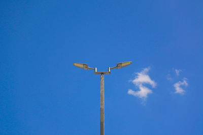 Low angle view of cross on pole against clear blue sky