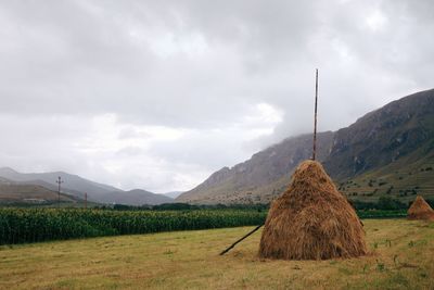 Hay bales on field against cloudy sky