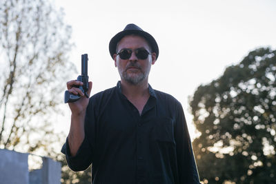 Low angle view of man holding gun against sky