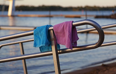 Close-up of padlocks hanging on railing against sea