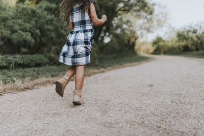 Low section of carefree girl running on dirt road