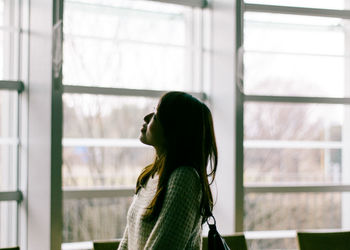 Side view of a young woman looking at window