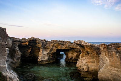 Rock formation in sea against sky