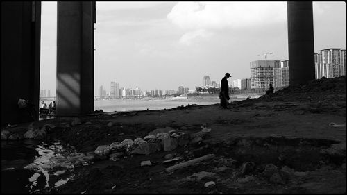 Man standing on rock in city against sky