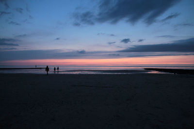 Silhouette man standing on beach against sky during sunset