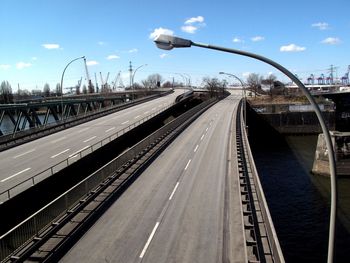 Railroad tracks by road in city against sky