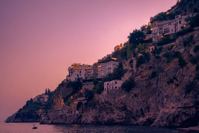 Building by sea against clear sky at sunset