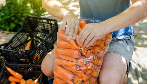 A farmer is packing freshly picked carrots into bags for sale. freshly harvested carrots. 