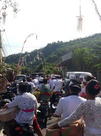 Rear view of people on street against sky