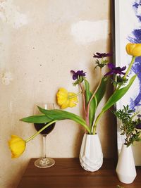 Close-up of wineglass by flower vase on table