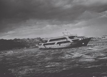 Boats in sea against cloudy sky