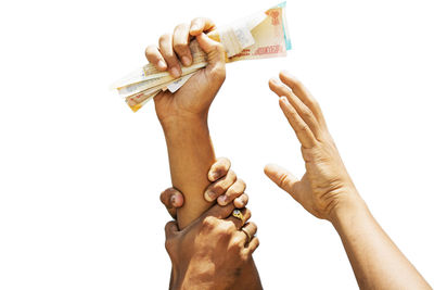 Low angle view of hand holding paper over white background