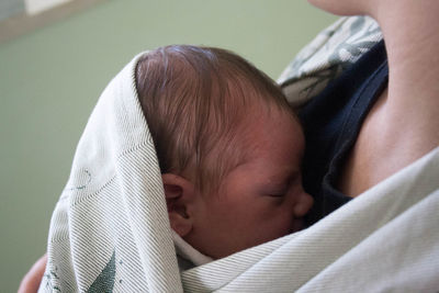 Cropped image of woman holding baby while standing at home