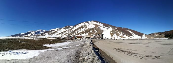 Scenic view of snowcapped mountains against clear blue sky