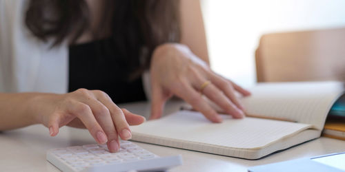 Midsection of woman using smart phone on table