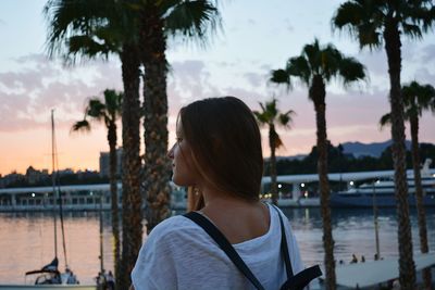 Rear view of young woman by sea during sunset