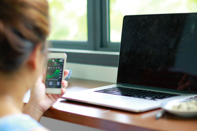 Midsection of woman using smart phone on table