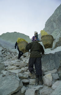 Rear view of men on rock against sky