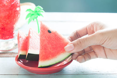 Cropped hand having watermelon slices on table