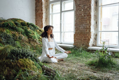 Side view of young woman sitting on field