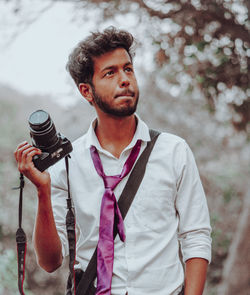 Young man looking away while standing outdoors