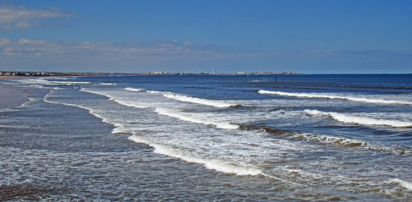 Scenic view of waves rushing towards shore against sky