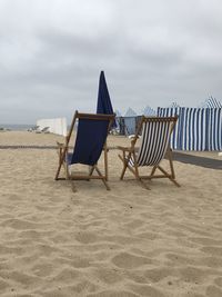 Chairs on beach against sky