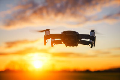 Close-up of silhouette camera against sky during sunset