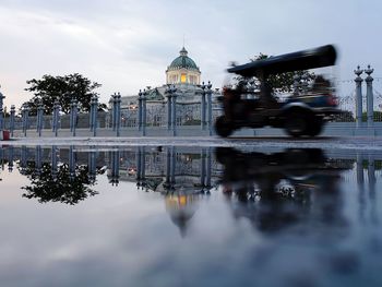 Reflection of building and tuk-tuk in puddle of water