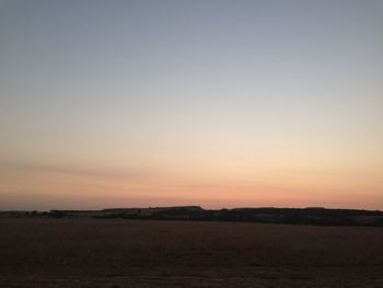 Scenic view of field against clear sky during sunset