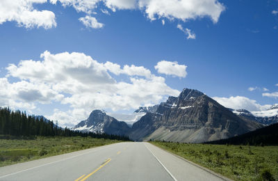 Road by mountains against sky
