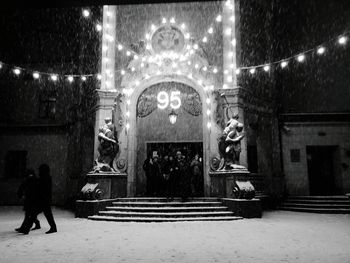 Rear view of people in illuminated building at night