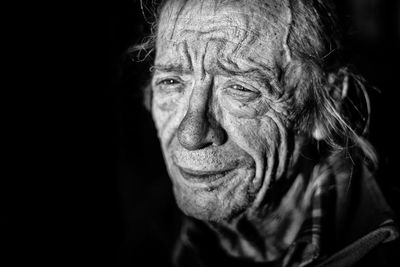 Close-up of crying senior man looking away against black background