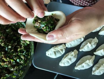 Cropped hand of man preparing dumplings on table