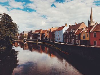 Buildings by river against sky