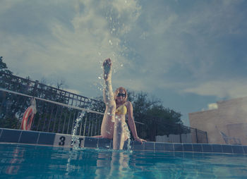 Woman enjoying in swimming pool against sky