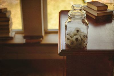 Close-up of glass jar on table inside dandelions