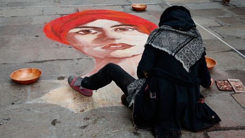 Full length portrait of woman standing against wall