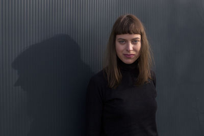 Portrait of young woman standing against wall