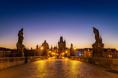 River amidst illuminated buildings against sky at dusk