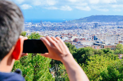 Rear view of man photographing cityscape against sky