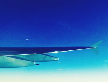 Cropped image of airplane flying over blue sky