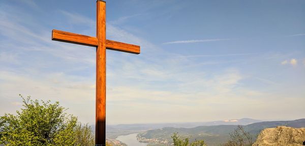 Low angle view of cross on mountains against sky