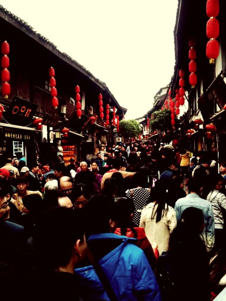 PEOPLE ON STREET AGAINST BUILDINGS IN CITY