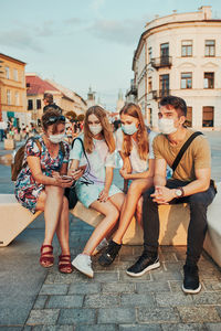 Family spending time together sitting in the city center. girls wearing the face masks